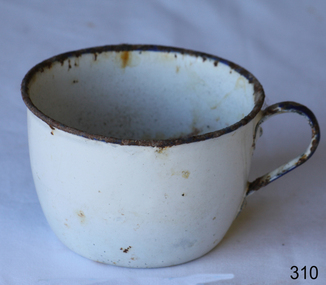 A white round enamel cup or mug with handle. Partly rusty.