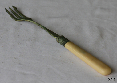 A long metal fork with a bone handle. The fork has three prongs.