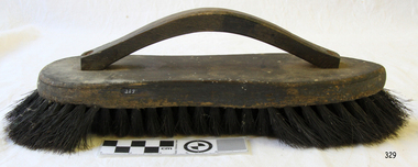 Brush has wooden handle and top, and black bristles.