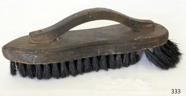 Brush with wooden spine and handle and black bristles that are longer at one end