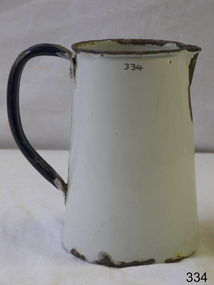 White metal enamel jug, with dark metal rim and dark blue handle, tapering inward towards top.