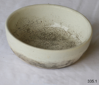 A small round white ceramic bowl, badly crazed and stained.