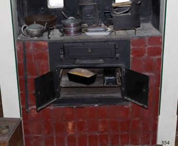Iron combustion stove with drop-down access to fuel box and double doors for the oven. Imbedded in surrounding brickwork.