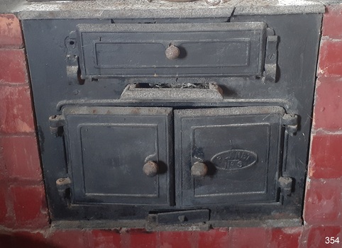 Cast iron stove with three positions for cooking on top, fire box below with ash tray, and oven below, and damper