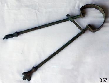 Brass fire tongs with claw shaped ends and a holding clip to keep the two parts together..