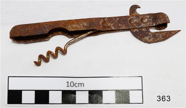 Old fashioned metal can opener, combined with a bottle opener, and corkscrew seated in the handle.
