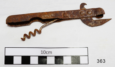 Old fashioned metal can opener, combined with a bottle opener, and corkscrew seated in the handle.