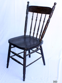 Wooden dark varnished dining chair with four vertical stretchers, and two rungs running the whole way around the legs, although at different heights. 