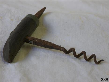 Metal corkscrew with spike, and with wooden handle that is partly broken. Very rusty.  