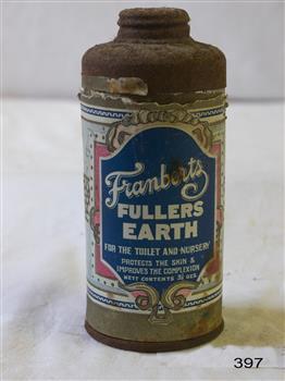 A round metal container with a perforated lid, with a coloured label indicating that it  originally contained Fuller's Earth.