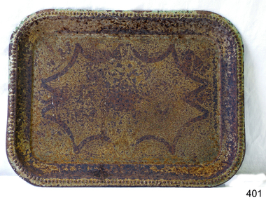 An oblong tin tray with an abstract pattern showing on the base. Rusty.