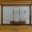 Ship model in glass case with wooden frame. Wooden model has no sails.