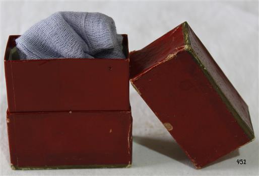 A maroon colour cardboard box with lid, containing medical gauze.