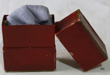 A maroon colour cardboard box with lid, containing medical gauze.