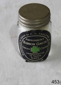 A gauze bandage inside a tround glass jar with metal screw lid.