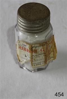 A gauze bandage inside an octagonal glass jar with metal screw lid.