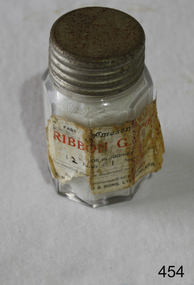 A gauze bandage inside an octagonal glass jar with metal screw lid.