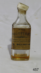 A clear glass oblong bottle with lid,  Empty.