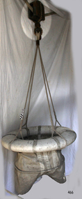Breeches buoy suspended from hawser line on a traveller block. Similar to a zip wire.
