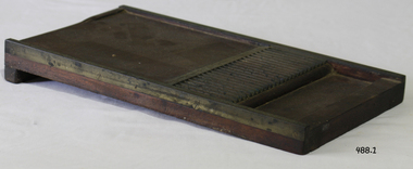 A sloping wood and brass board with grooving, enabling pills to be made.