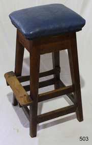 Stool is strong construction. It has a footrest, well worn, and a purple fabric covered padded seat.