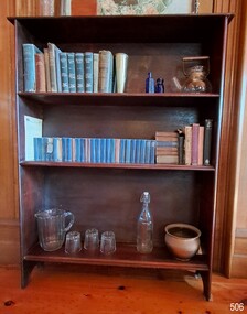 Timber bookshelf with three shelves. Set of Prayer Books, and Jug and Glasses set are on display.