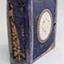 A small sized book with a blue cover and gold trimming.