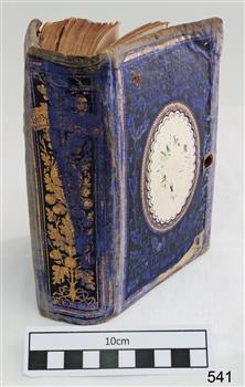 A small sized book with a blue cover and gold trimming.