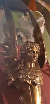 Figure's hair is crinkled, and there is a bodice of feathers moulded into the metal.