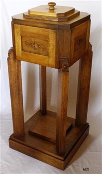 Timber pedestal with flat square base, legs in each corner, supporting square box with cut corners, decorative pattern on sides and lid on top.