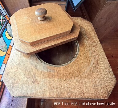 Wooden font and lid, slightly open to reveal empty cavity