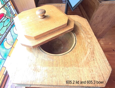 The copper bowl or ewer is not installed in the font's cavit and is revealed below the open lid