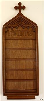 Rectangular wooden board with a cross mounted on its decorative peaked top. Narrow internal shelves.