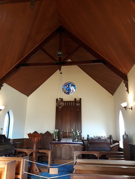 Round commemorative window installed in wall above altar in Chapel