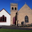 Weatherboard building  beside sandstone building, sandstone bell tower between themg with 