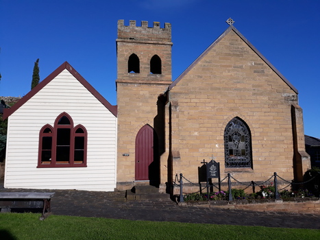 Weatherboard building  beside sandstone building, sandstone bell tower between themg with 
