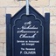 Blue painted sign with lettering, a white cross above the writing, fixed to upright posts.