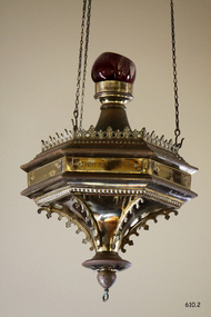 Decorative round brass and glass lamp with ruby glass bowl. It is suspended on three chains.