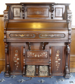 Timber organ with decorative panels and two carpet-covered foot pedals