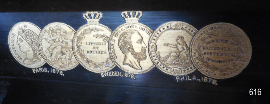Gold decals representing the exhibitions in which this model of organ was on display