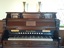 Keyboard has five octaves and eleven stoppers. Gold maker's name medallions are above the keyboard.