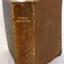 Textured brown leather cover with embossed gold text on spine, and impressed cross emblem on front
