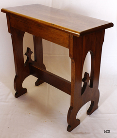 Polished timber stool with flat angled seat and legs on the short ends, braced close to the feet. 