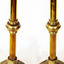 A pair of brass candlestick holders with scalloped dish at top, central knob on stem and decorative base