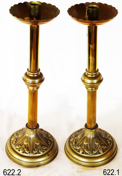 A pair of brass candlestick holders with scalloped dish at top, central knob on stem and decorative base