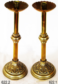 A pair of brass candlesticks with scalloped dish at top, central knob on stem and decorative base