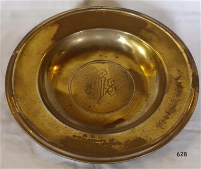 Round brass plate has motif and inscription in the centre