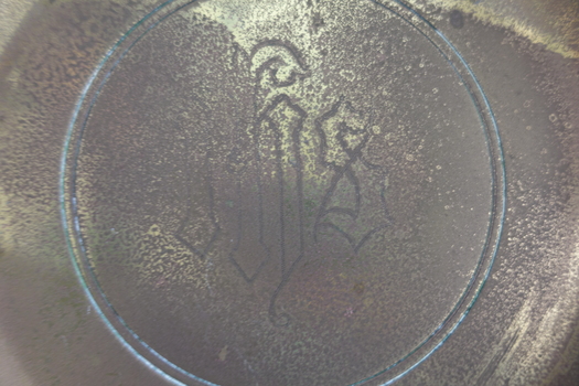 Inscription of intertwined letters is embossed on the plate