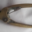 Metal mechanism has two arms and has inscriptions. Flat pads on the end of the arms have cross hatching lines.