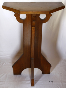 Wooden pedestal with four legs and top that is half a pentagon, made to fit against a wall